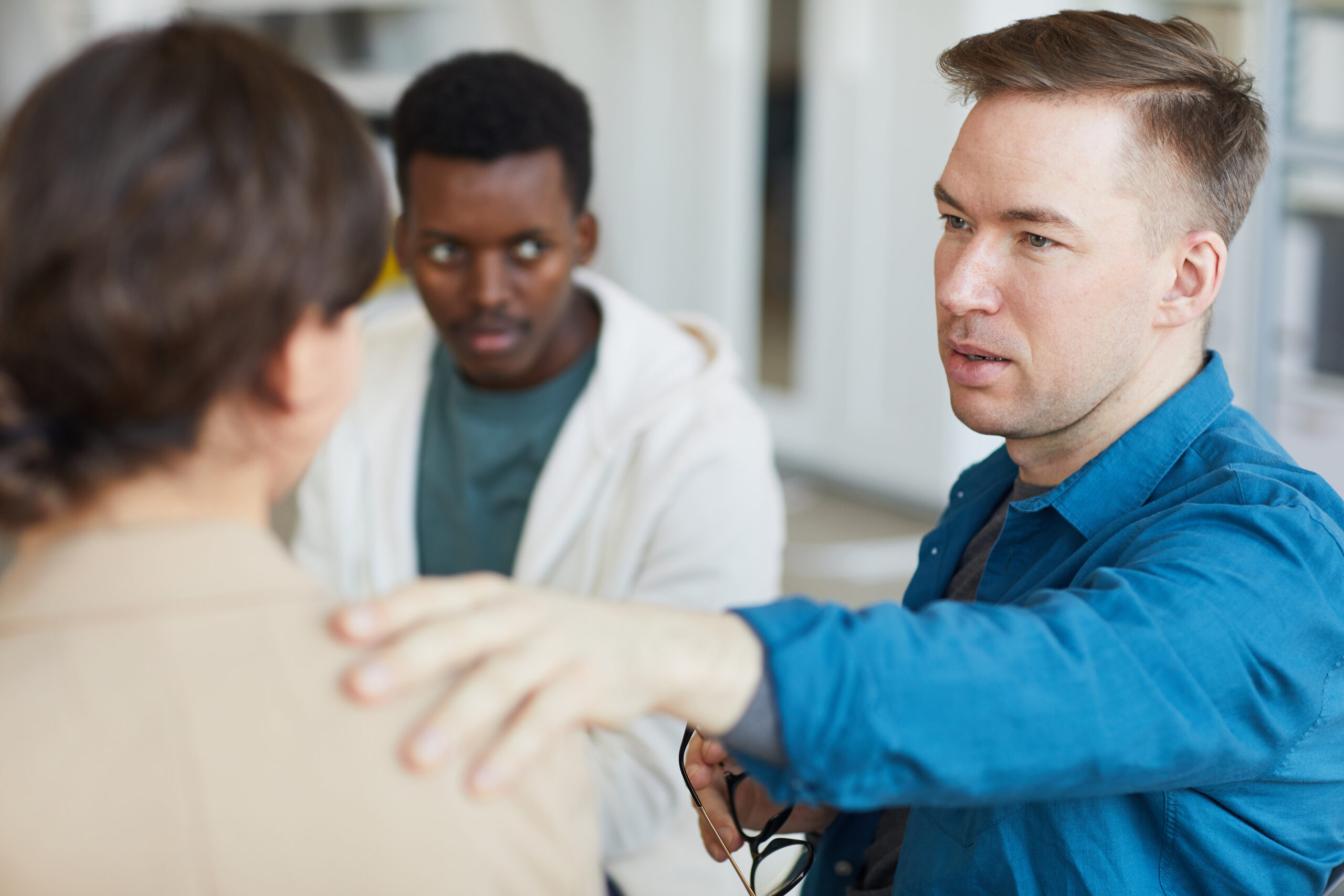 Portrait,Of,Adult,Man,Comforting,Woman,In,Psychology,Support,Group,